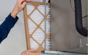 Image of a furnace technician holding an air filter.